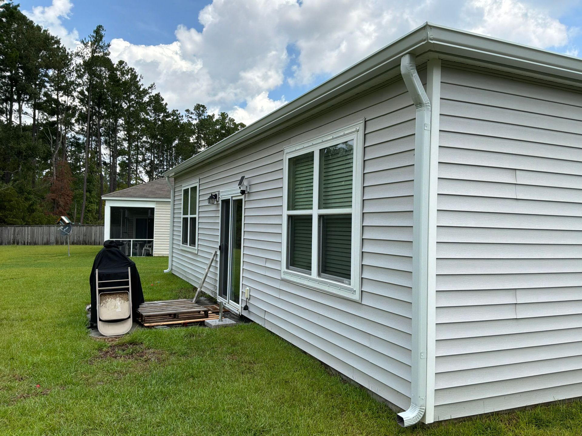 New downspout carrying water away from the wall of a Charleston home by Charleston Roofs and Windows