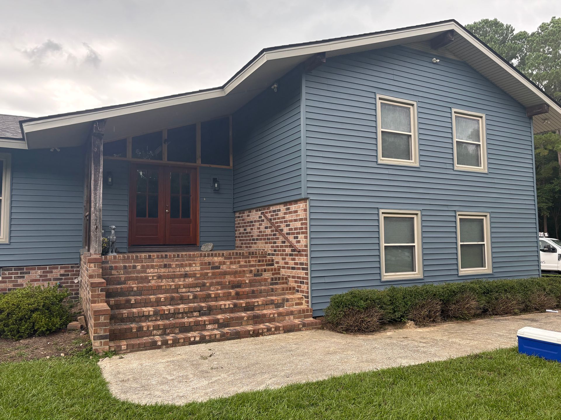 Blue house exterior with brick steps, front porch, and multiple windows