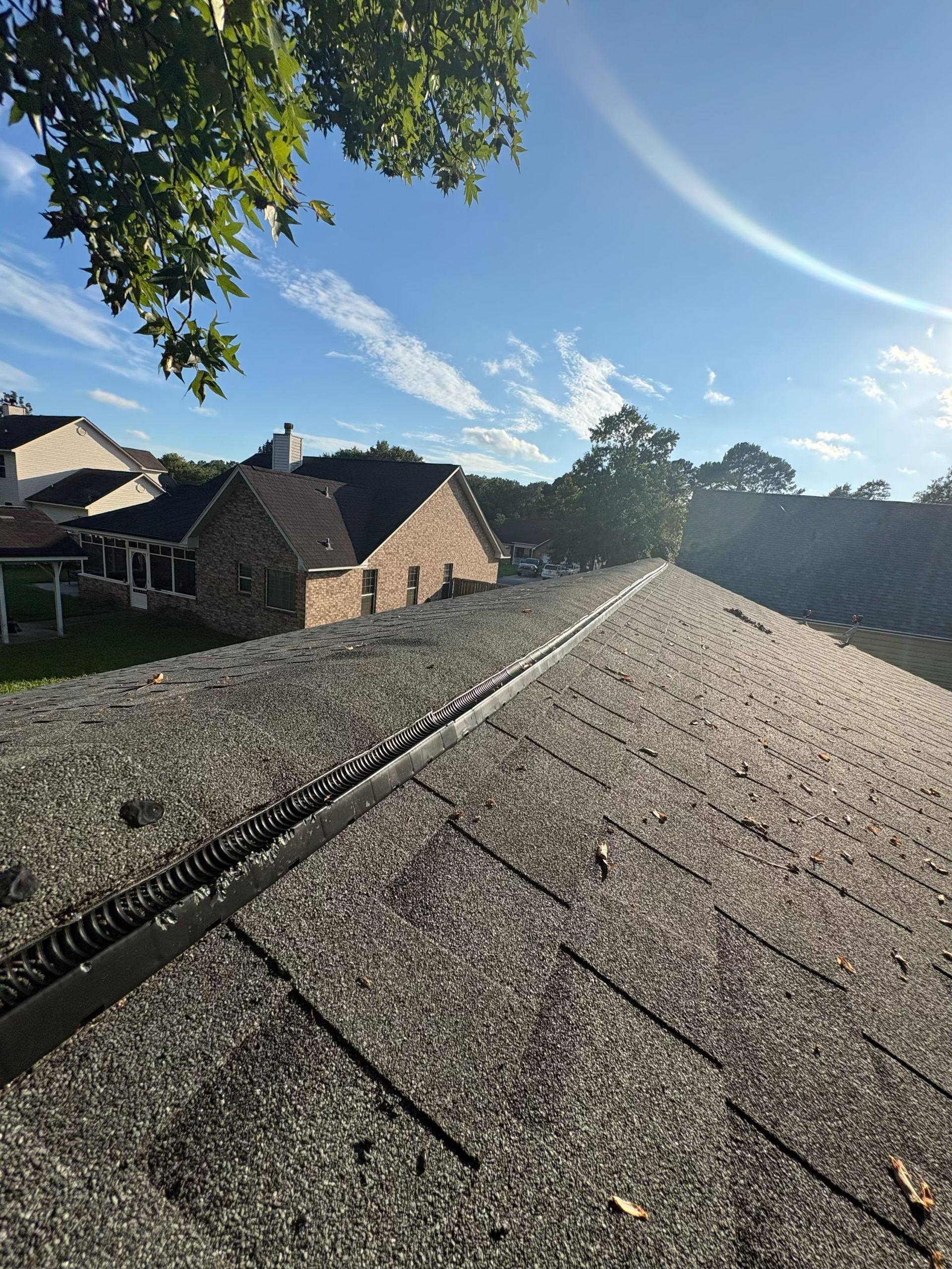 Rooftop with gravel surface beside stone cottages under a bright blue sky