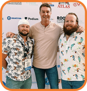 Three men smiling and posing at a branded event backdrop, with arms around each other.