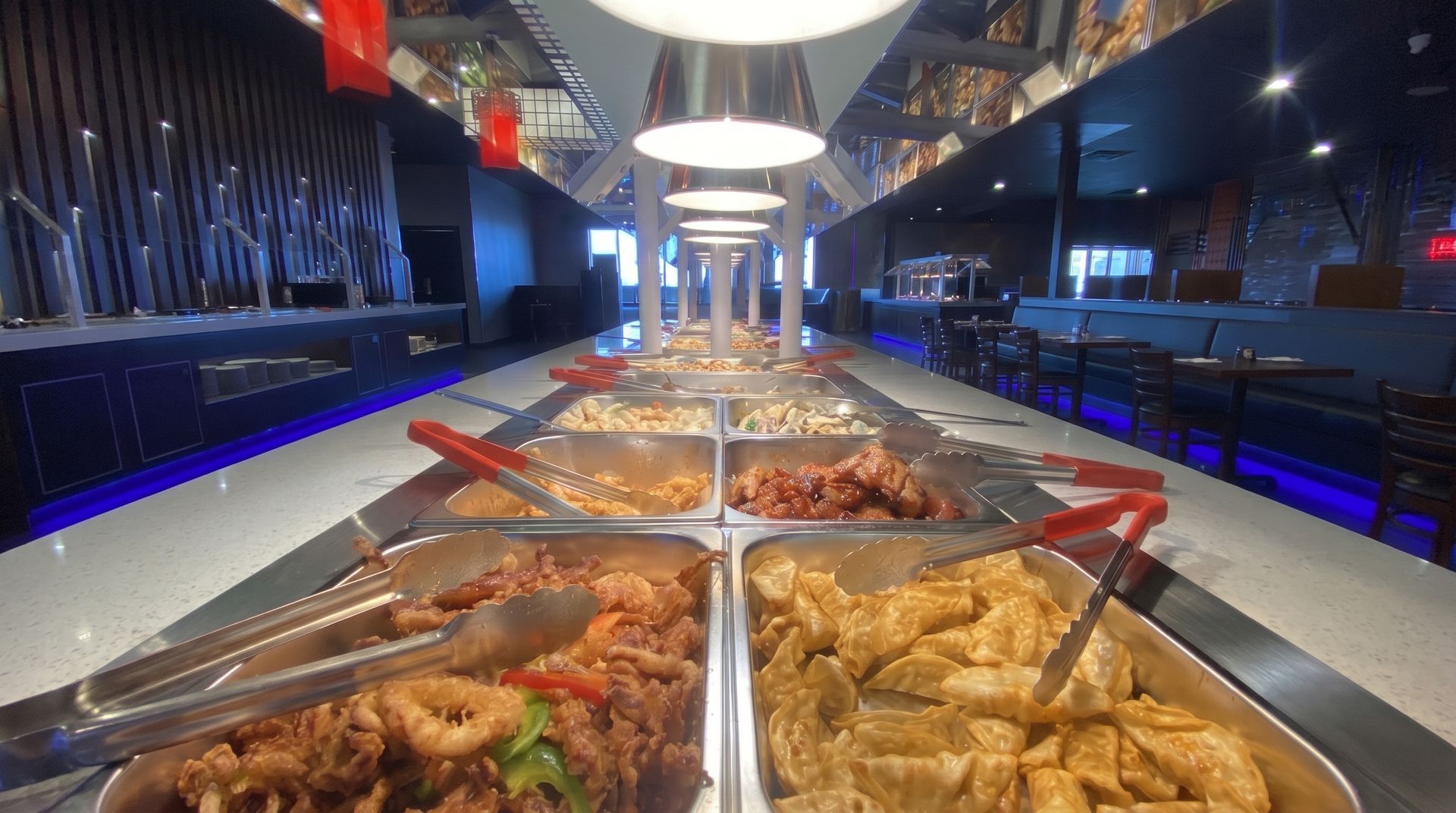 Buffet counter with trays of assorted hot food under bright lights in a modern restaurant