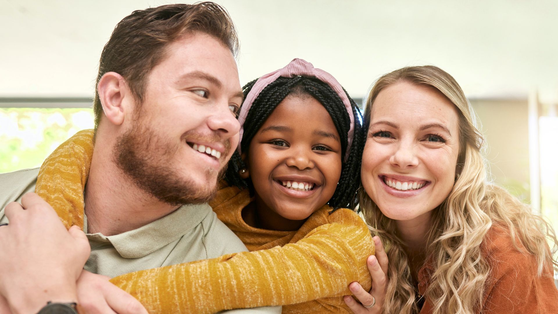 A man and a woman are hugging a little girl.