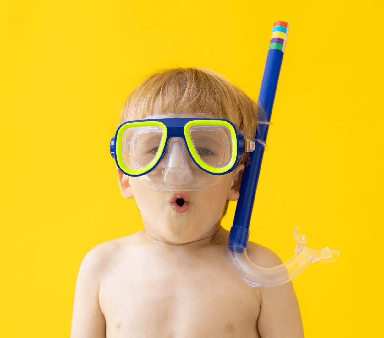 Blond child with snorkel mask and open mouth, against yellow backdrop, looking surprised.
