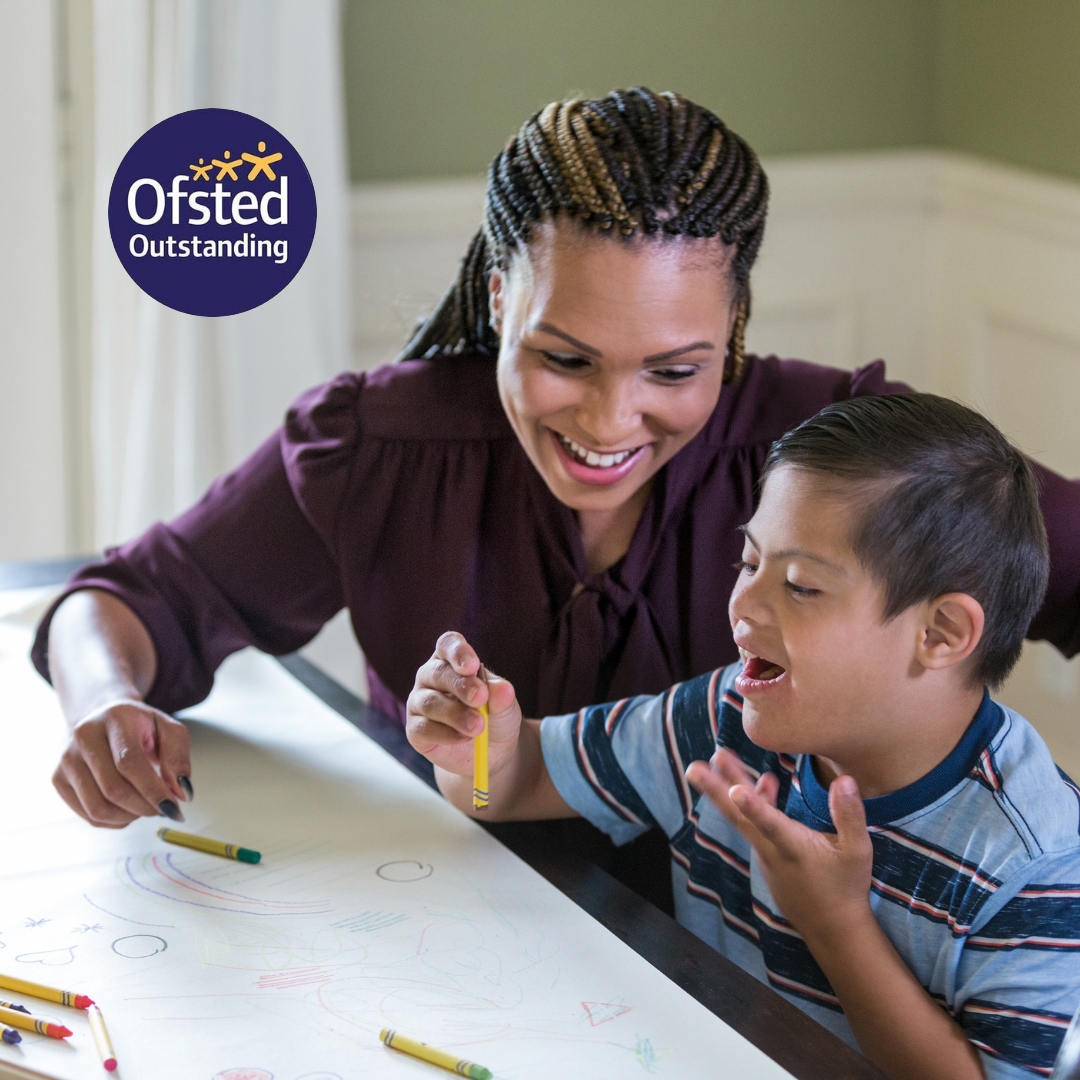 A woman is teaching a young boy how to draw with crayons ..