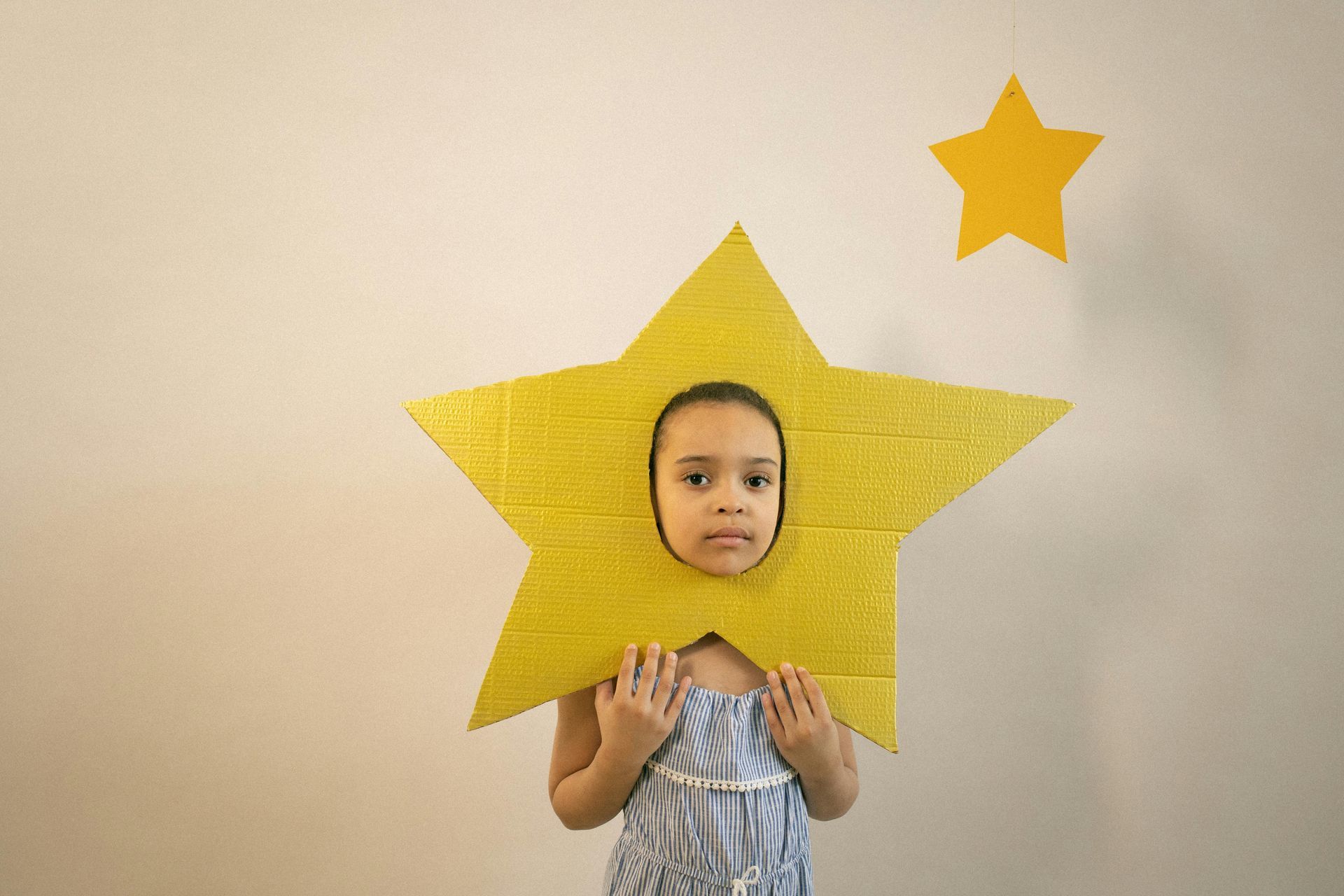 A little girl is wearing a yellow star on her head.