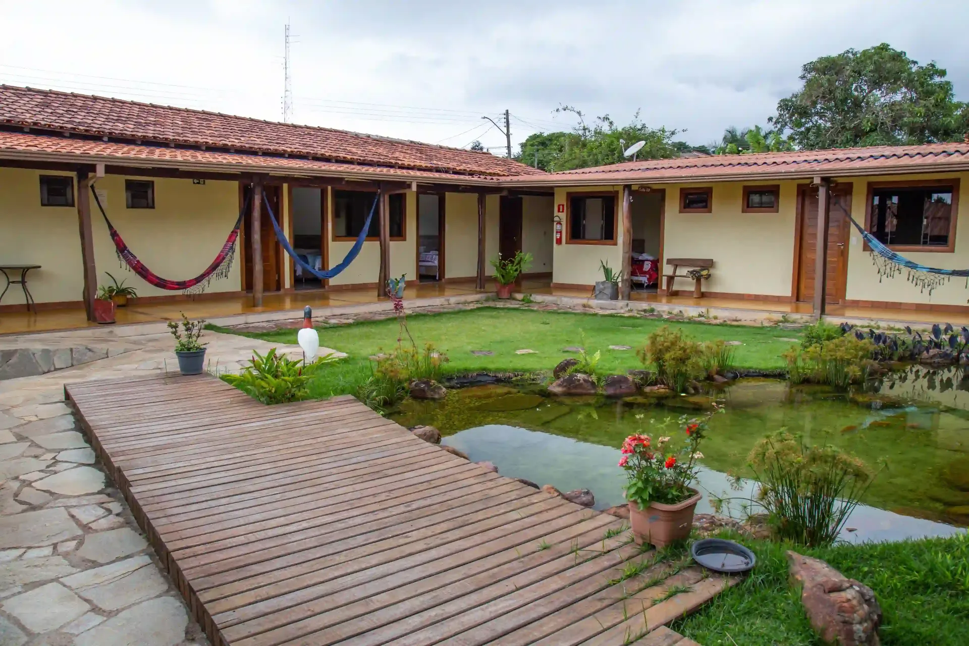 Uma casa com redes e um lago na frente. pousada-dos-guias