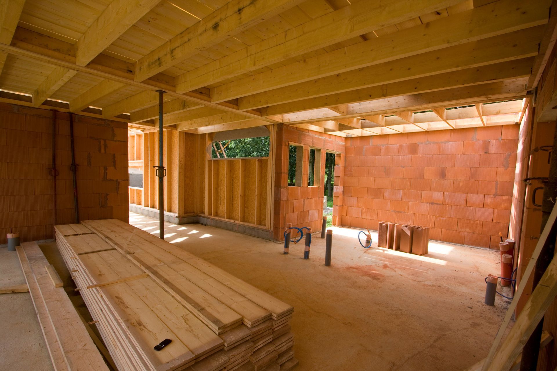 A room under construction with wooden beams and brick walls.