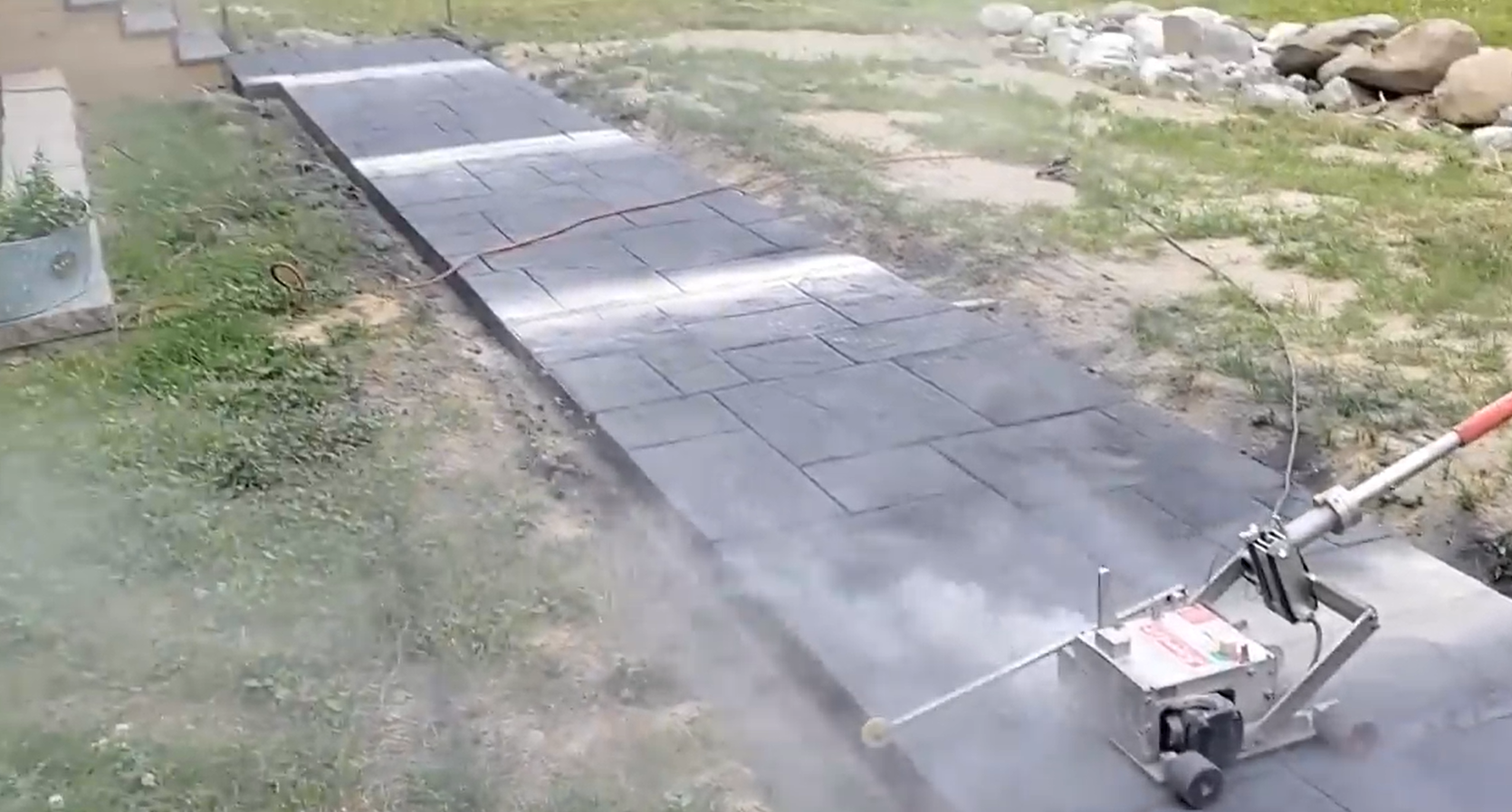 Fresh concrete sidewalk being smoothed out.