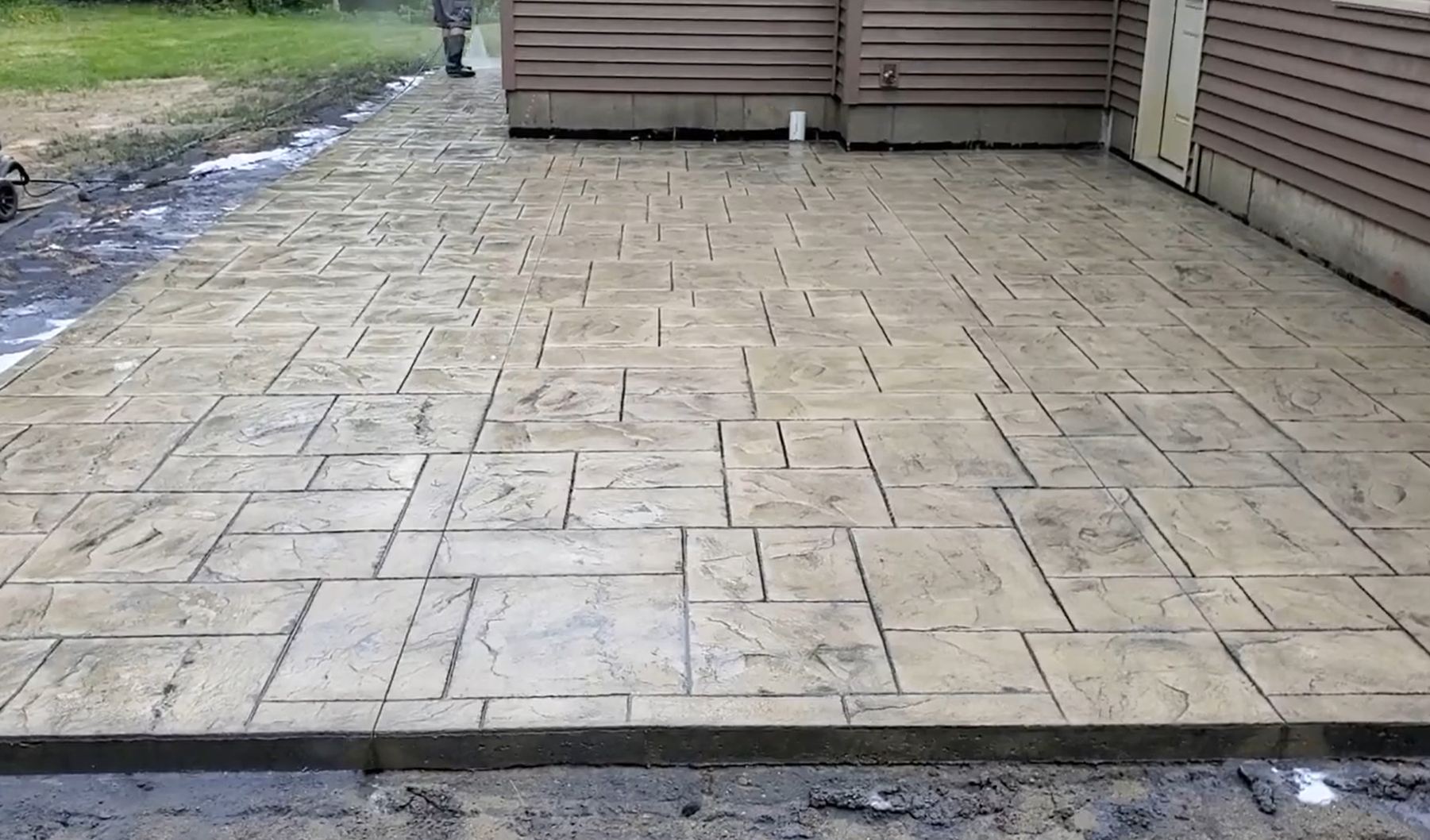 Crew member sealing after concrete patio has been stamped and stained.