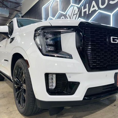 White GMC pickup truck in a showroom, front-left view with black grille and wheels