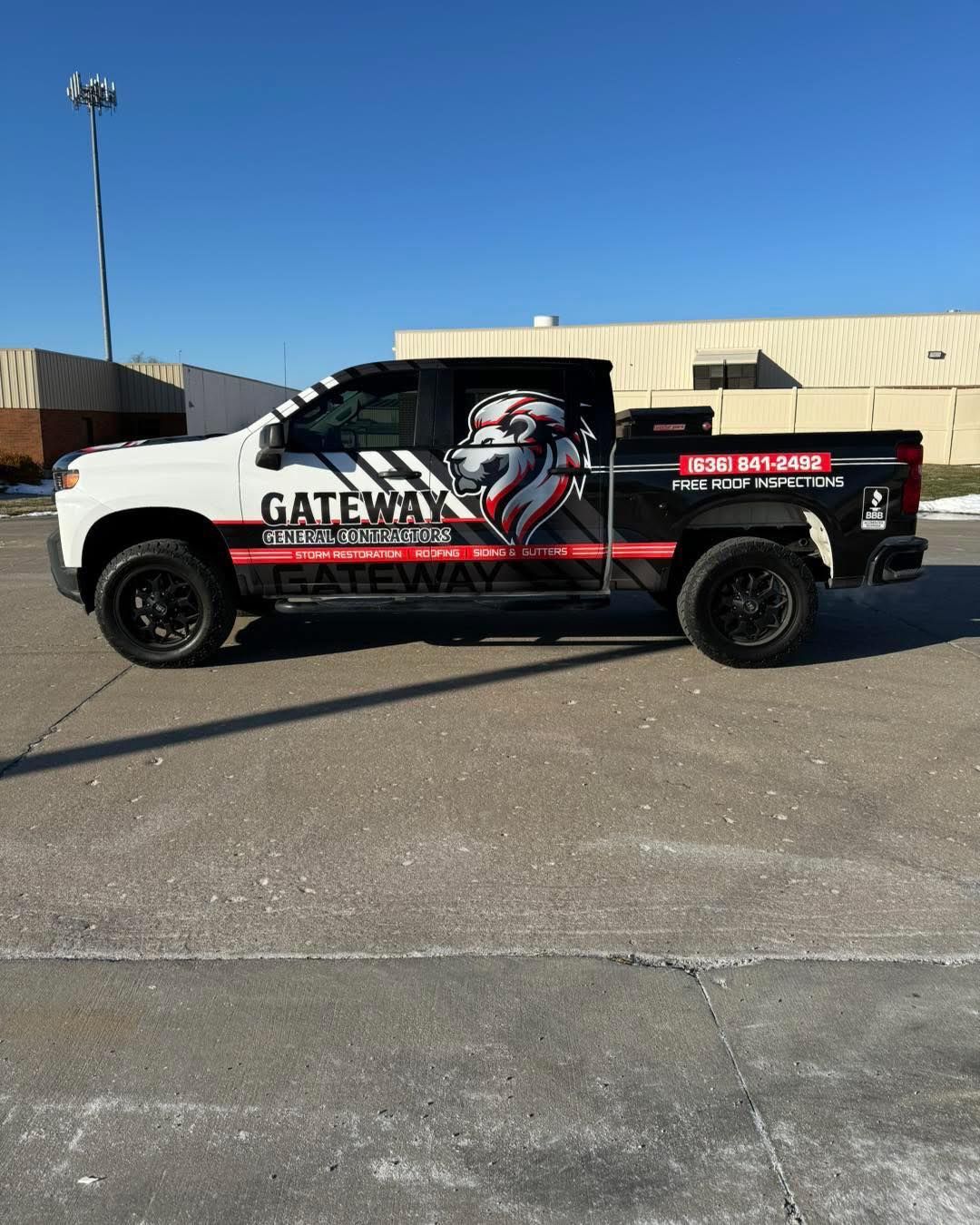 Black pickup truck with red and white graphics parked in an industrial lot under a clear blue sky