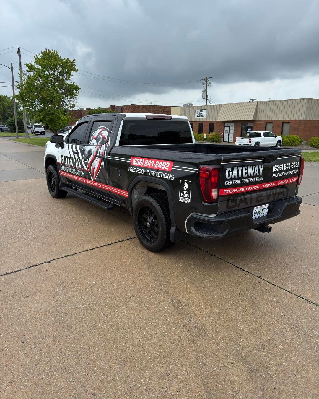 Black Gateway-branded pickup truck parked on a wet street under cloudy skies.