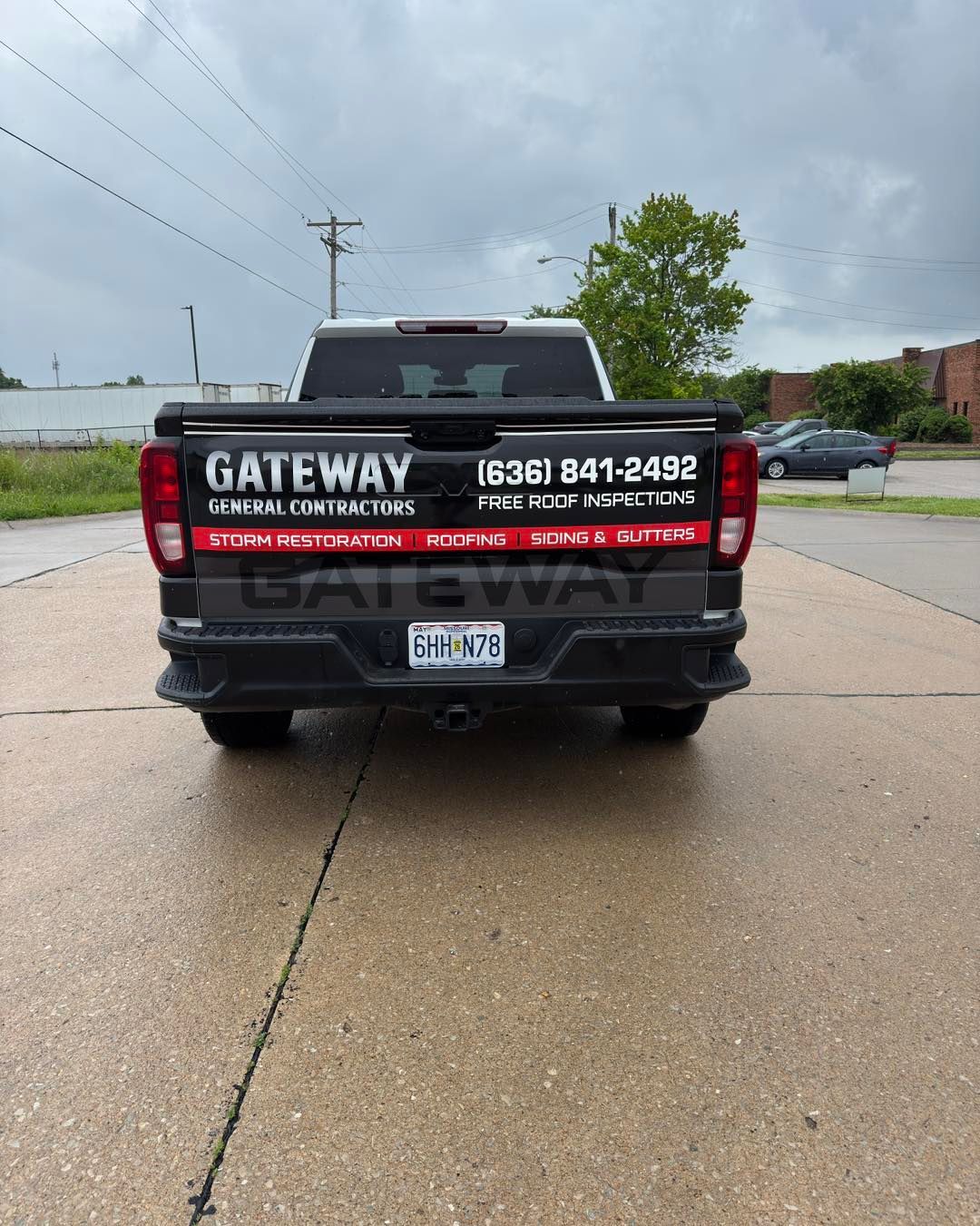 Black pickup truck with Gateway lettering on the tailgate parked on a wet residential street.