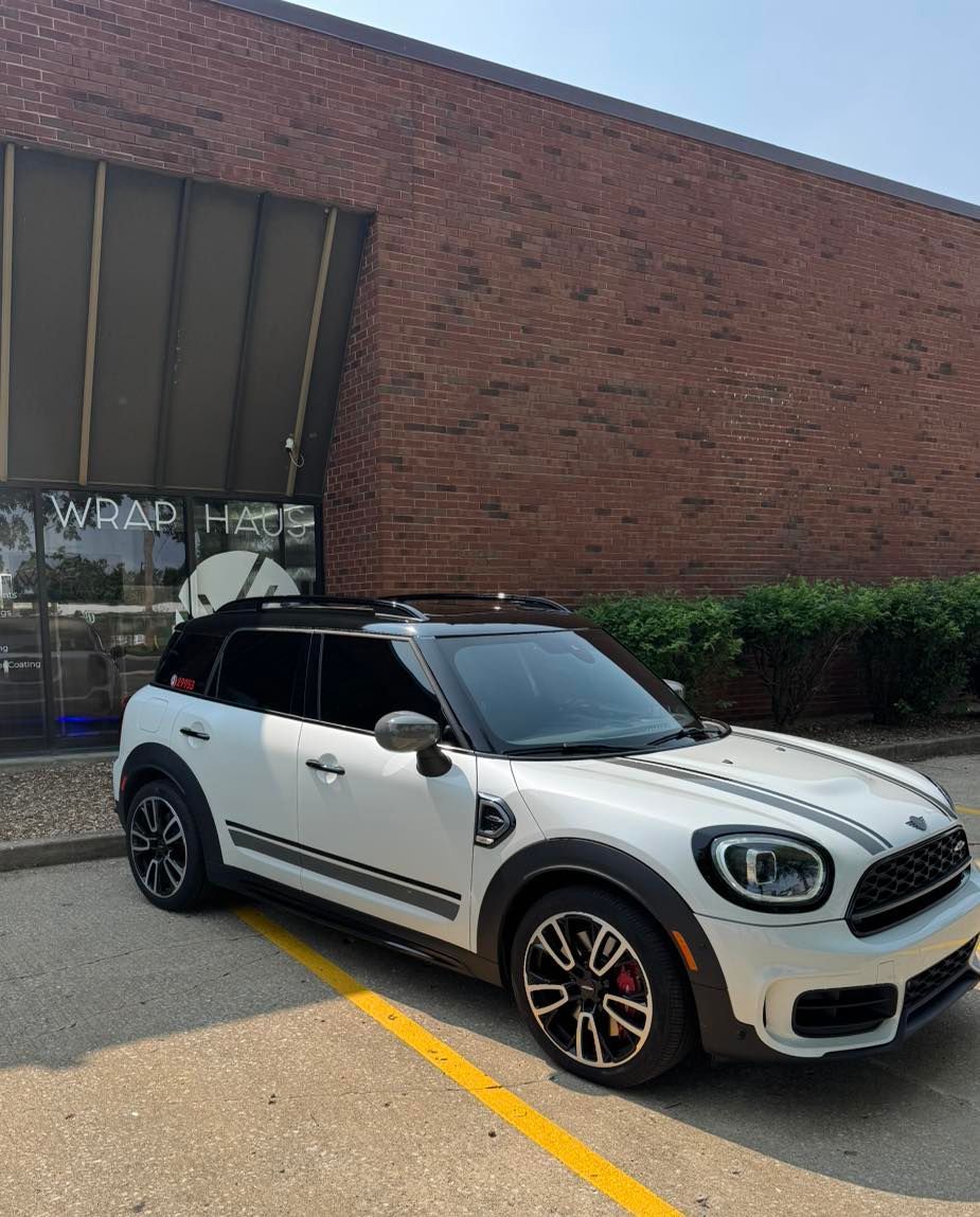 White Mini SUV parked outside a brick building, angled in a parking space.