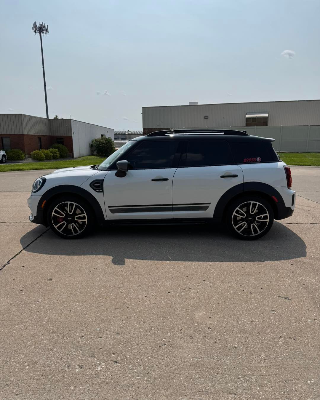 White SUV parked on a sunny street near industrial buildings