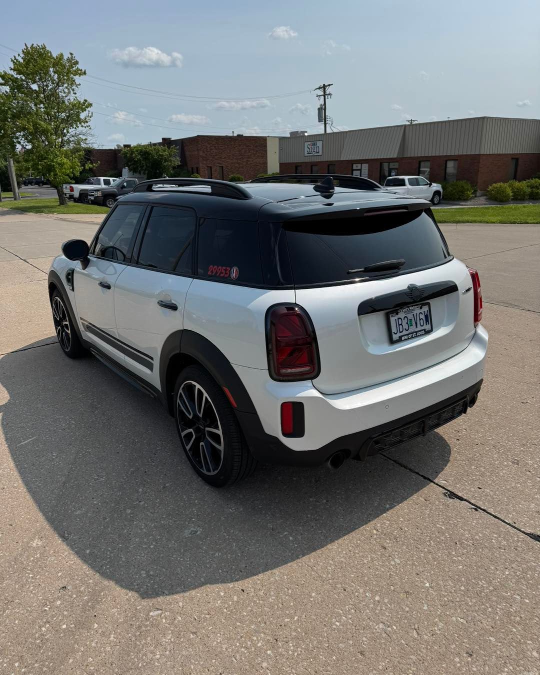 White Mini Cooper parked in a lot near a brick building on a sunny day.