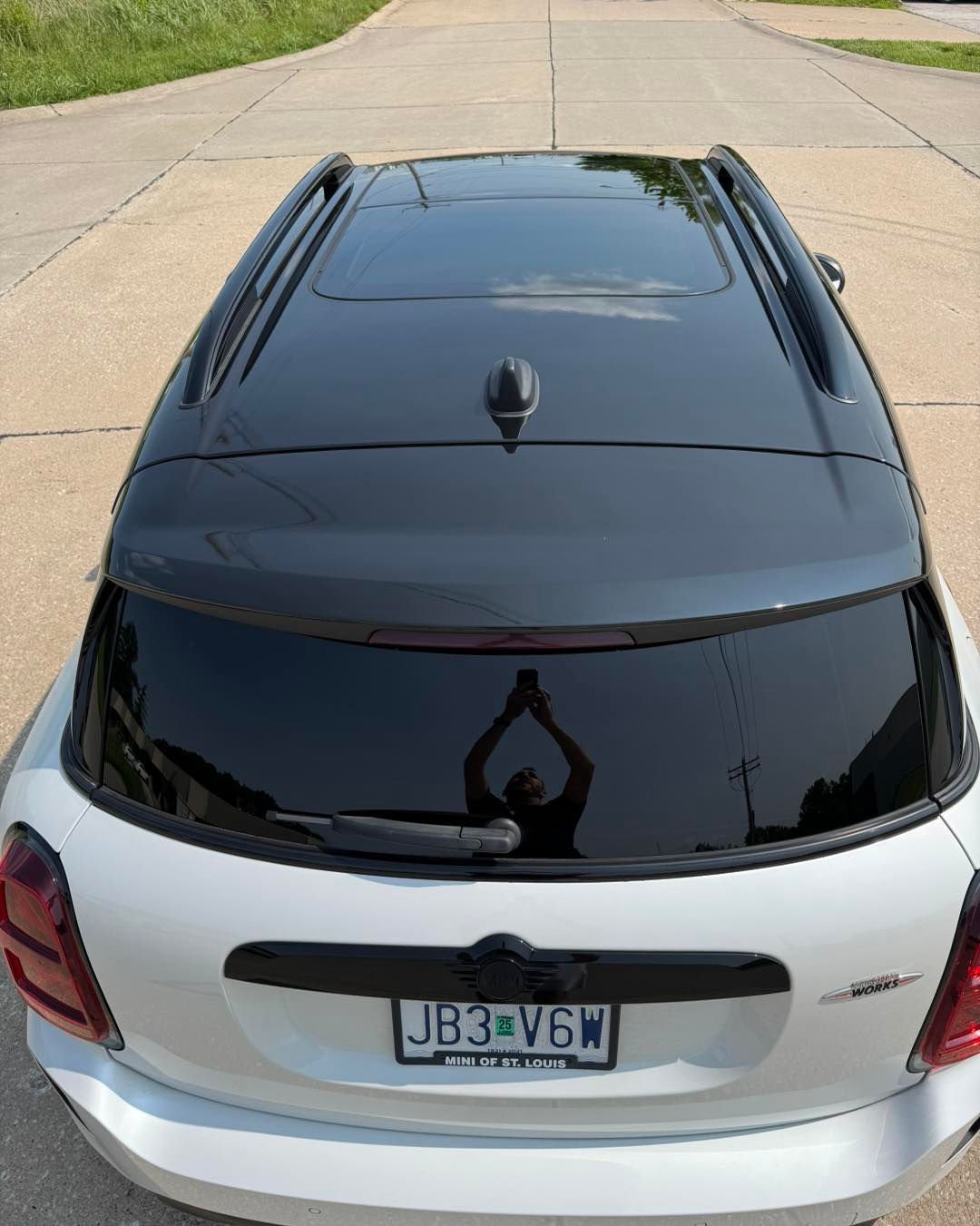 Overhead view of a white car with a black roof parked on a driveway