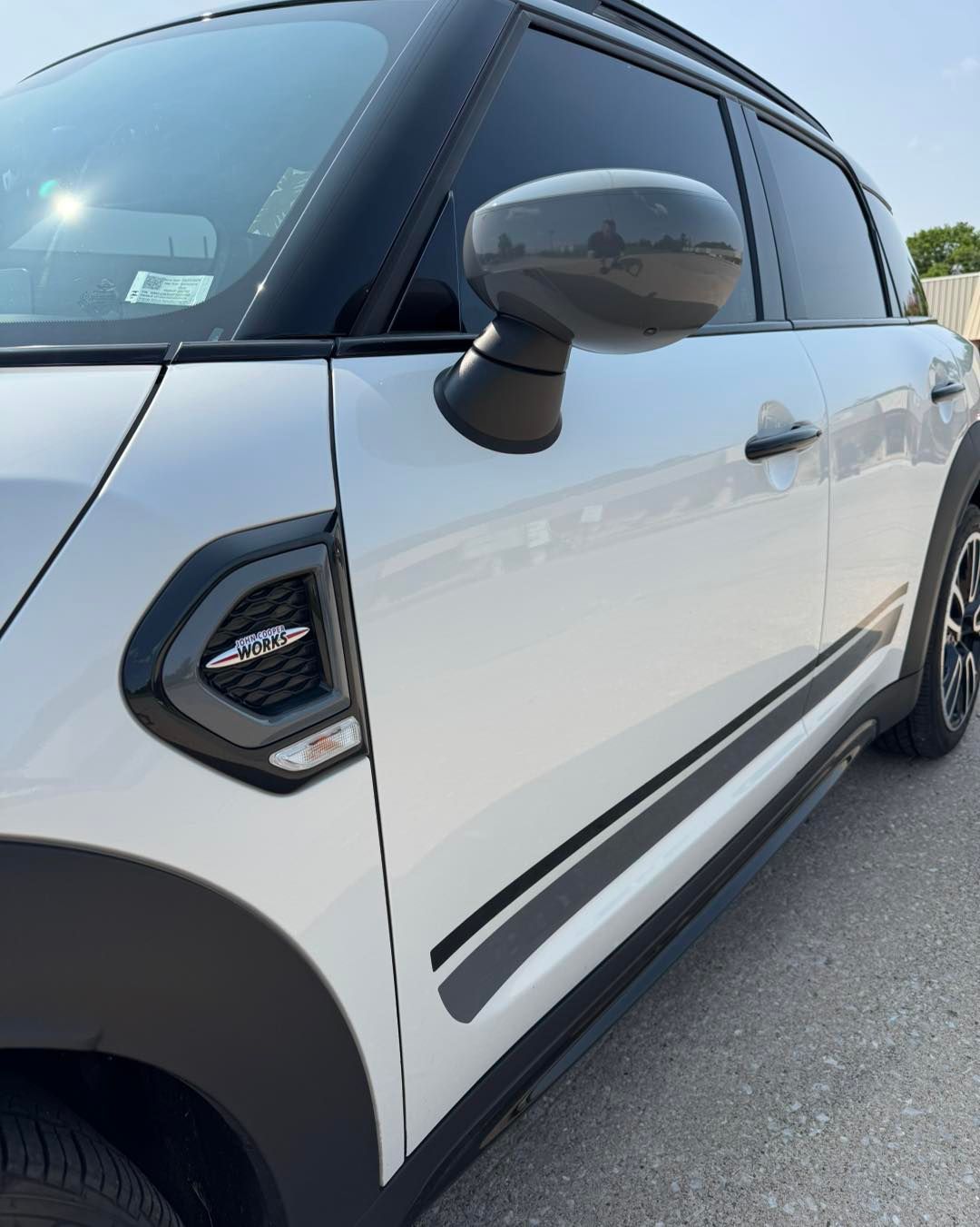 White compact SUV with black roof and trim, seen from the side in a parking lot.