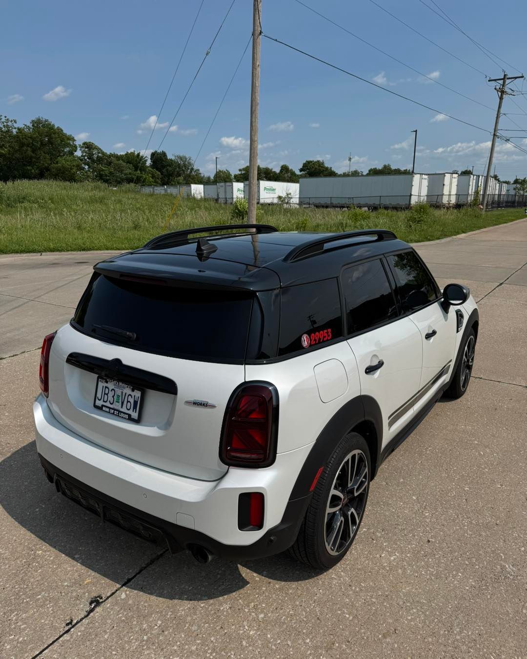 White SUV with a black roof parked on a roadside under power lines.