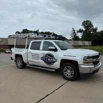White pickup truck with company logo parked on a driveway under cloudy skies