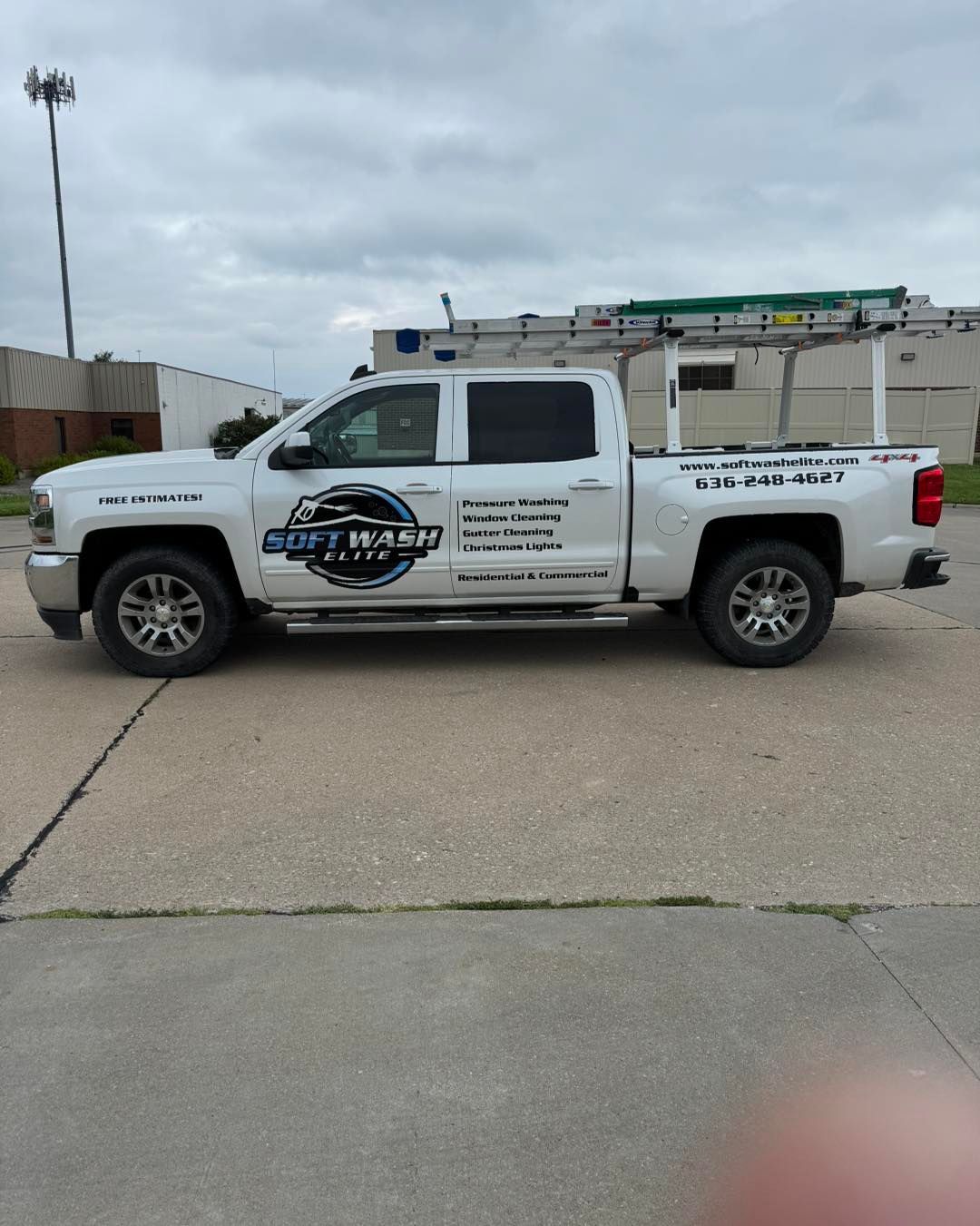 White pickup truck with company logo and lettering parked in a lot under an overcast sky