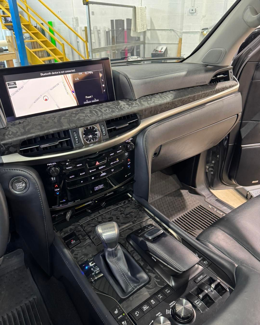 Car interior with dashboard, center console, touchscreen navigation display, and open passenger door