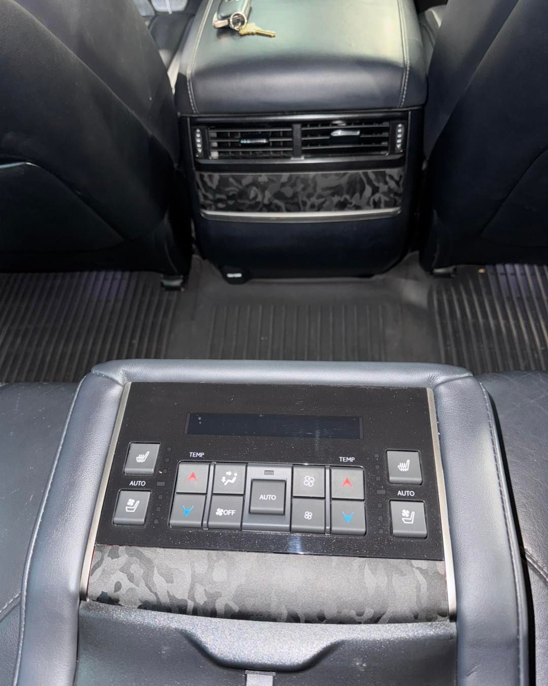 Rear-seat car control panel with climate buttons and vents in a black interior