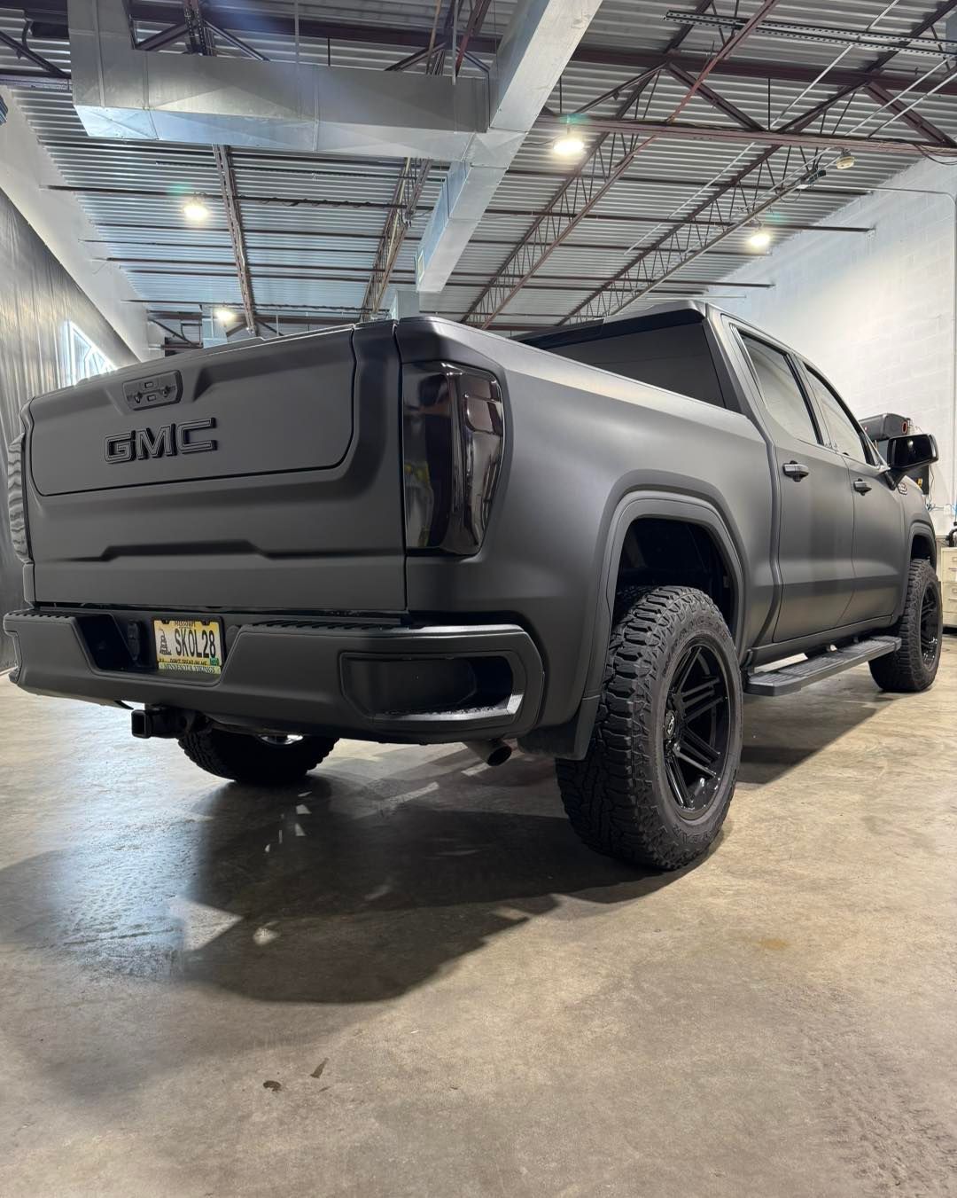 Matte black GMC pickup truck parked indoors under industrial lighting