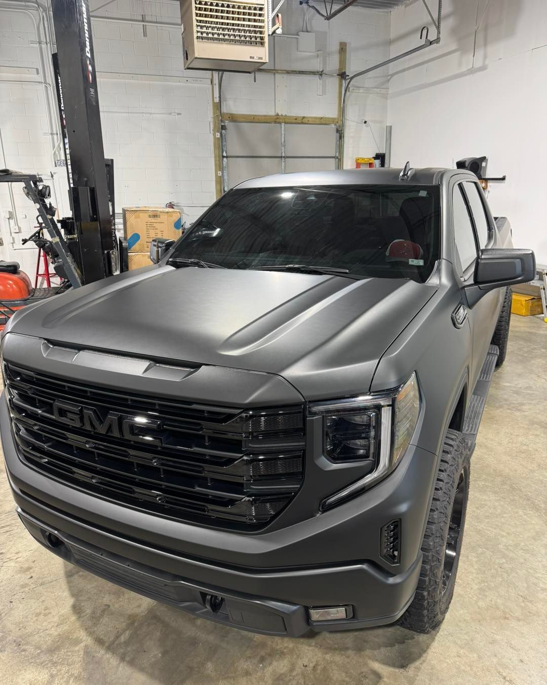 Black GMC pickup truck in a garage, front view with hood and grille visible.
