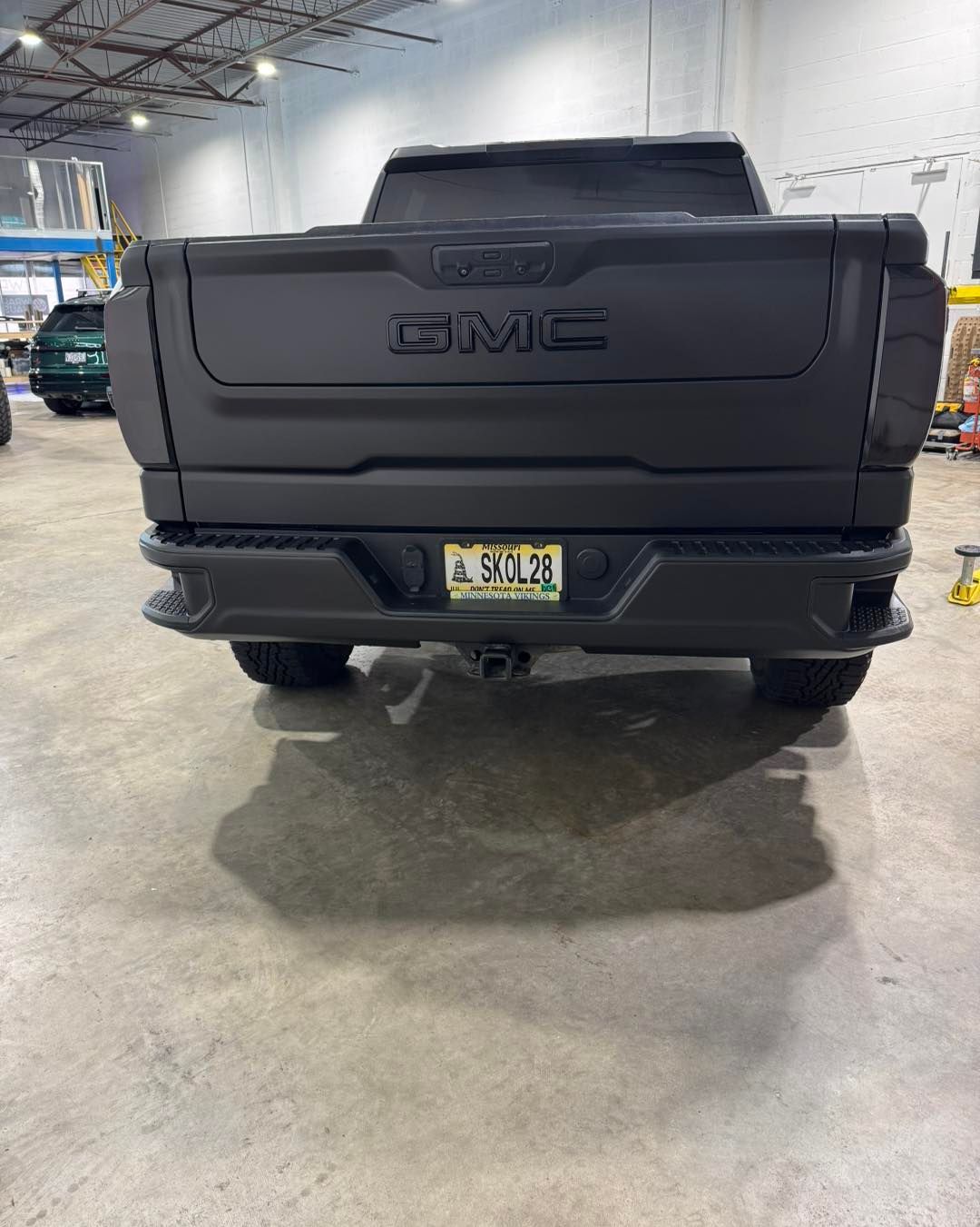 Rear view of a black GMC pickup truck inside a warehouse or auto shop