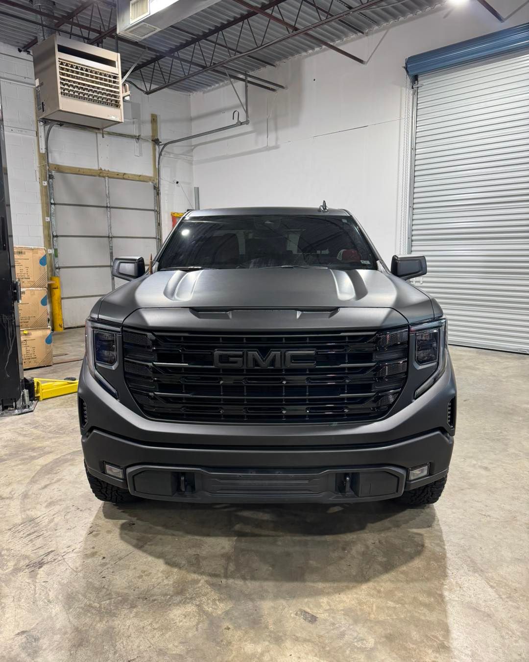 Black GMC pickup truck parked inside a warehouse garage.