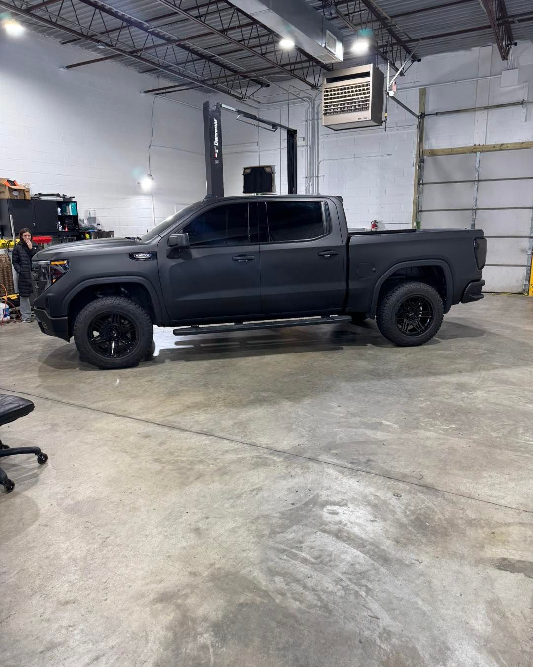Black pickup truck parked inside a warehouse garage.
