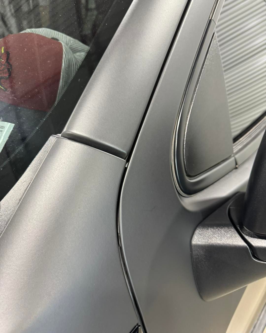Close-up of a silver car’s door pillar and window frame with a black trim seam