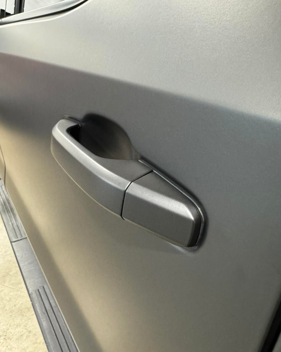 Close-up of a silver car door handle on a metallic gray vehicle.