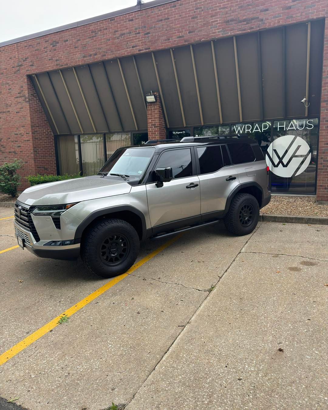 Silver SUV parked by a brick building with a Volkswagen logo on the wall