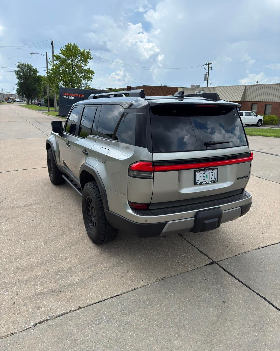 Gray SUV parked on a city street under a partly cloudy sky