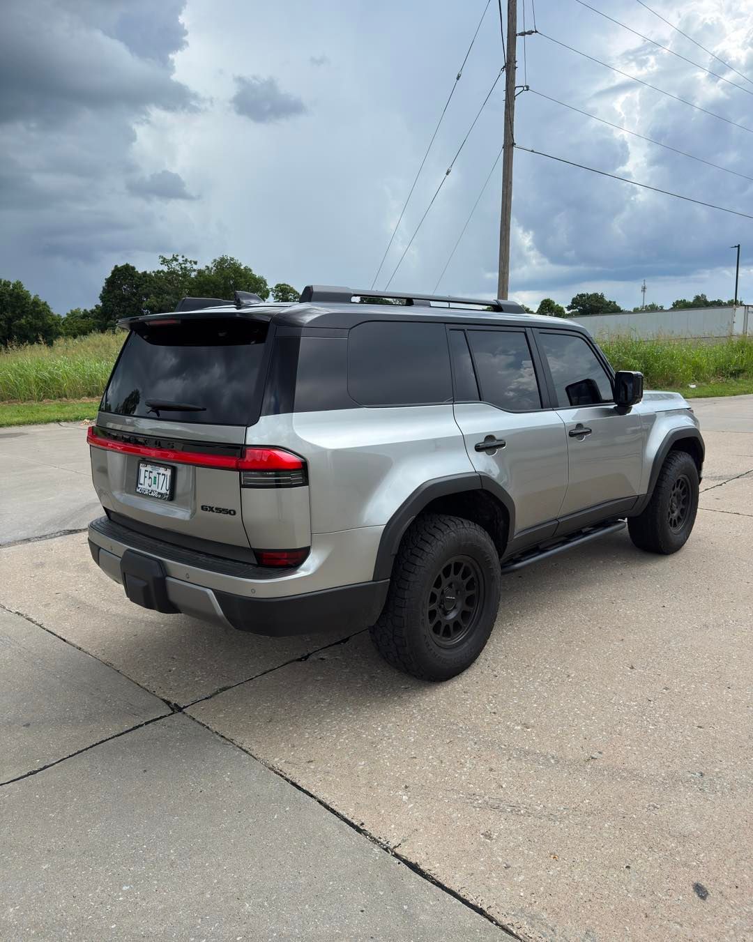 Silver SUV parked on a roadside under cloudy skies, rear three-quarter view
