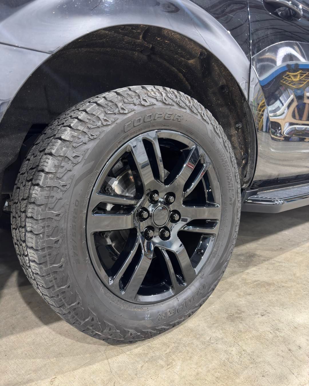 Black pickup truck wheel with off-road tire on a concrete floor