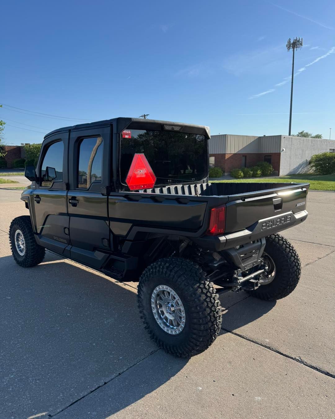 Black lifted off-road pickup truck parked on a sunny street, rear three-quarter view