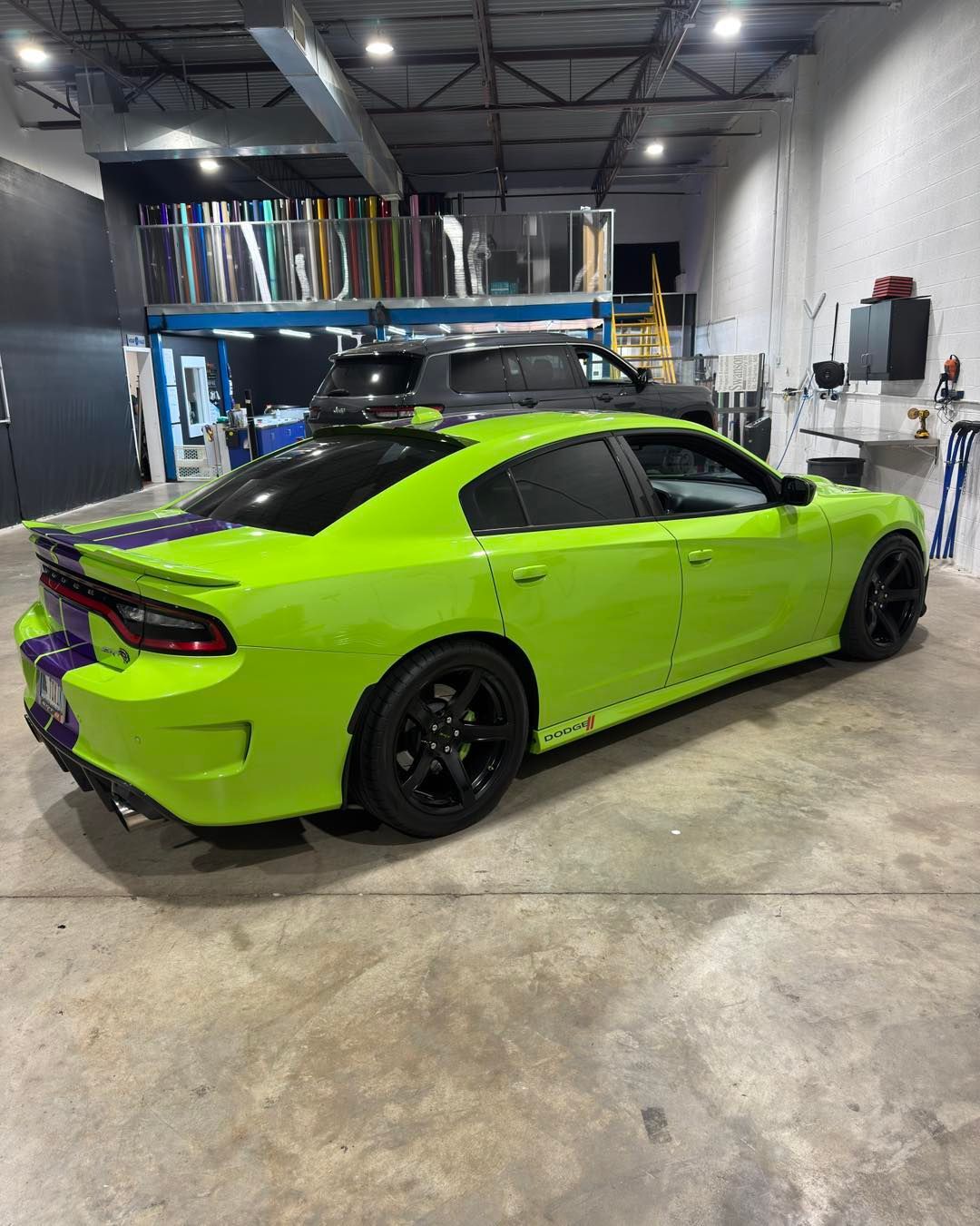Neon green sports car in a garage, shown from the rear side.
