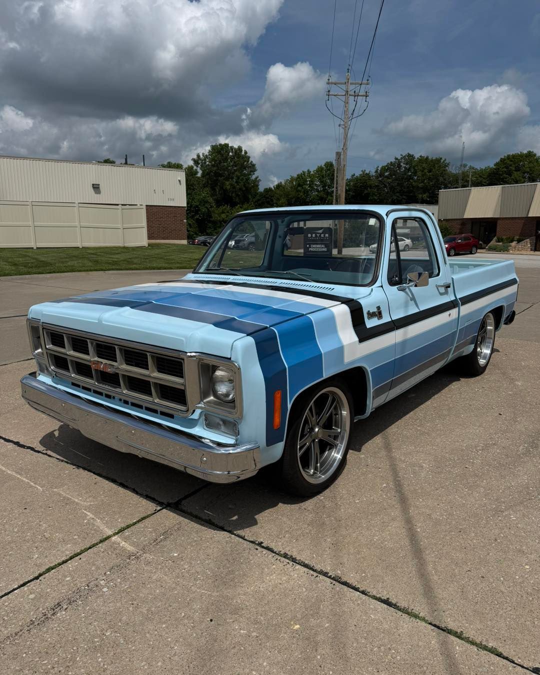 Classic blue-and-white pickup truck parked on a concrete lot under a cloudy sky.