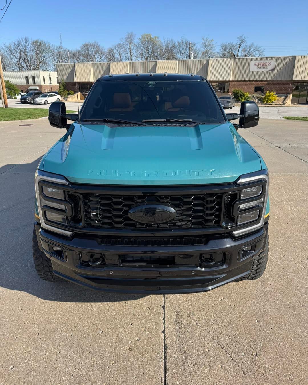 Front view of a turquoise Ford pickup parked in a lot on a sunny day