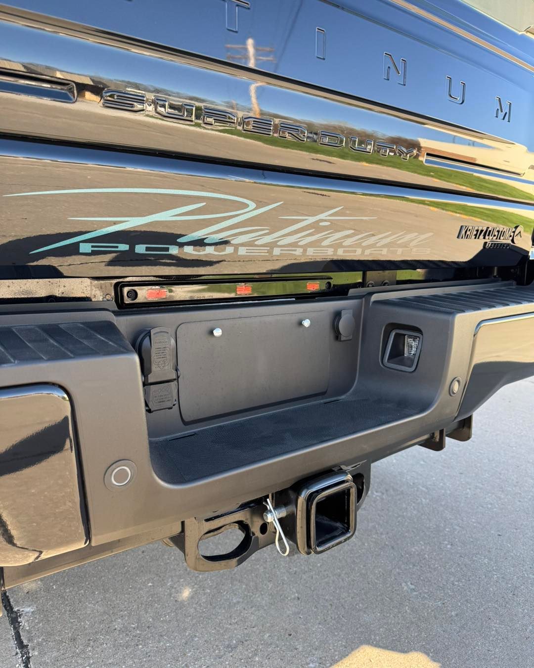Close-up of a black Lincoln SUV tailgate with chrome lettering and tow hitch in a parking lot