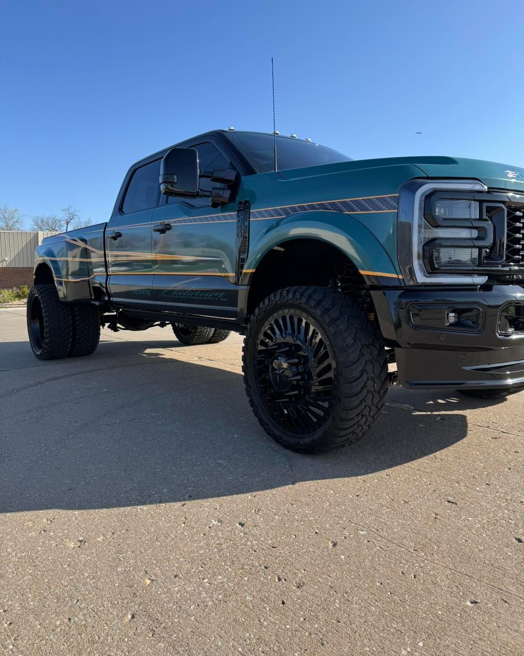 Lifted dark blue pickup truck parked on pavement under a clear blue sky