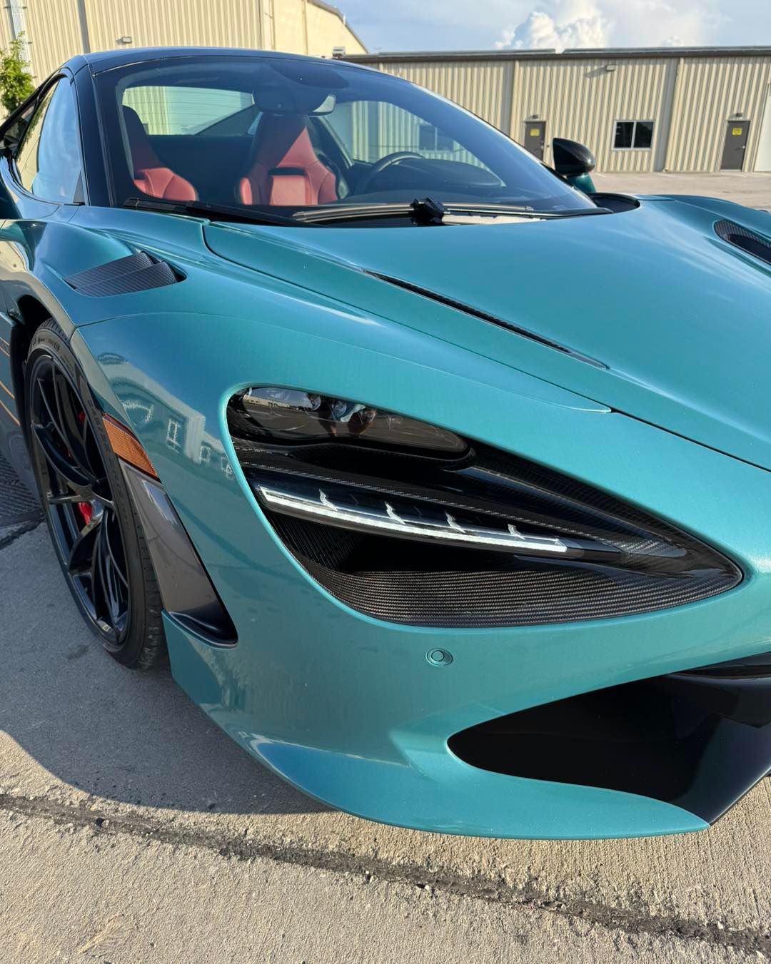 Turquoise sports car parked outdoors in sunlight, front-left view