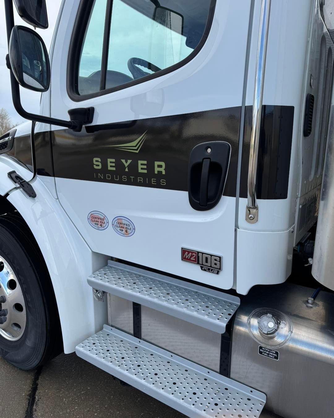 White semi-truck cab with black trim and silver steps, showing the side door and SEYER logo.