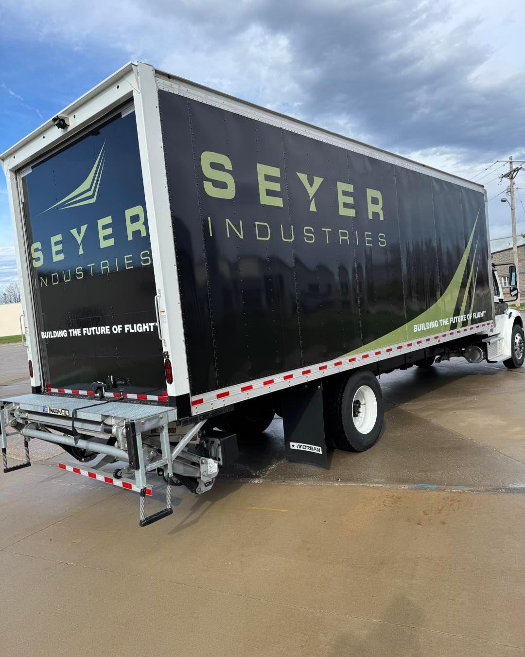 Black Seyer Industries box truck parked on a wet lot under cloudy skies