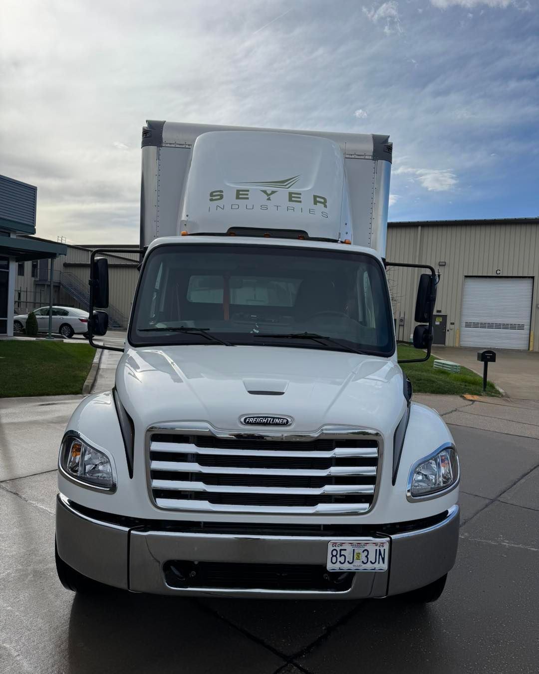 White delivery truck parked outside a warehouse on a cloudy day