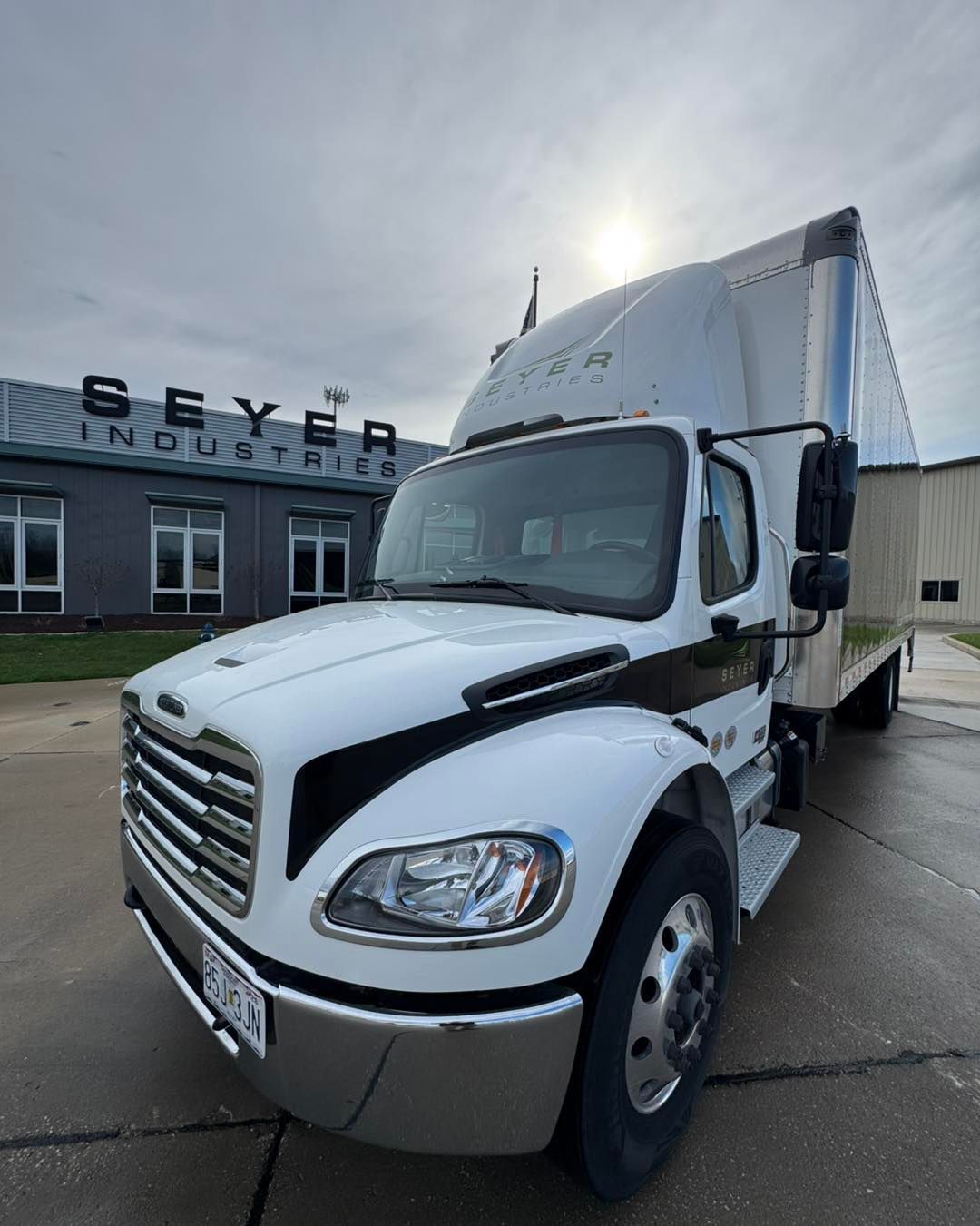White semi-truck parked outside a building with the “Beyer” sign under a cloudy sky