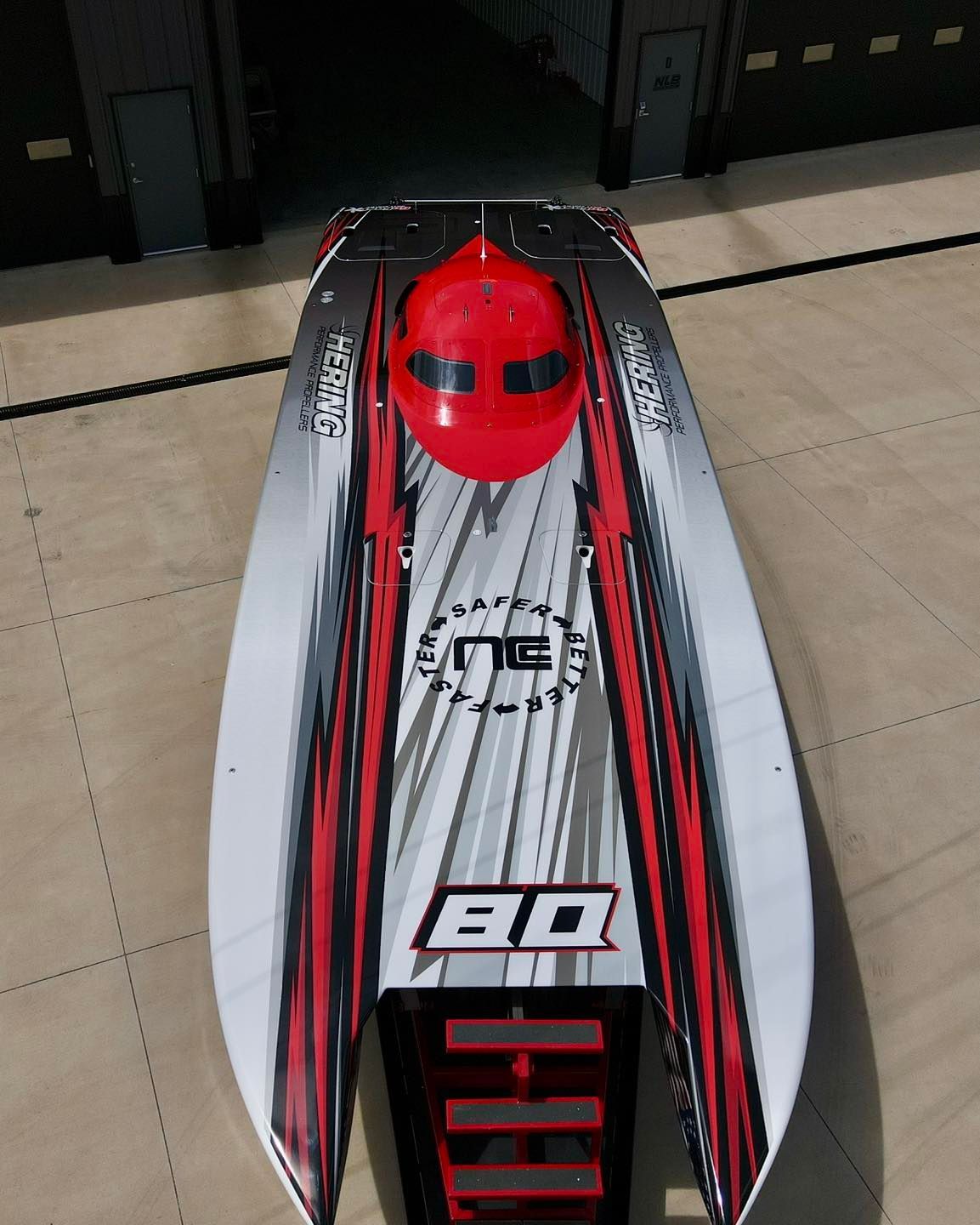 Red and white remote-control speedboat with a red canopy, viewed from above indoors.